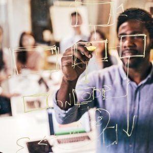 A man drawing on a glass board